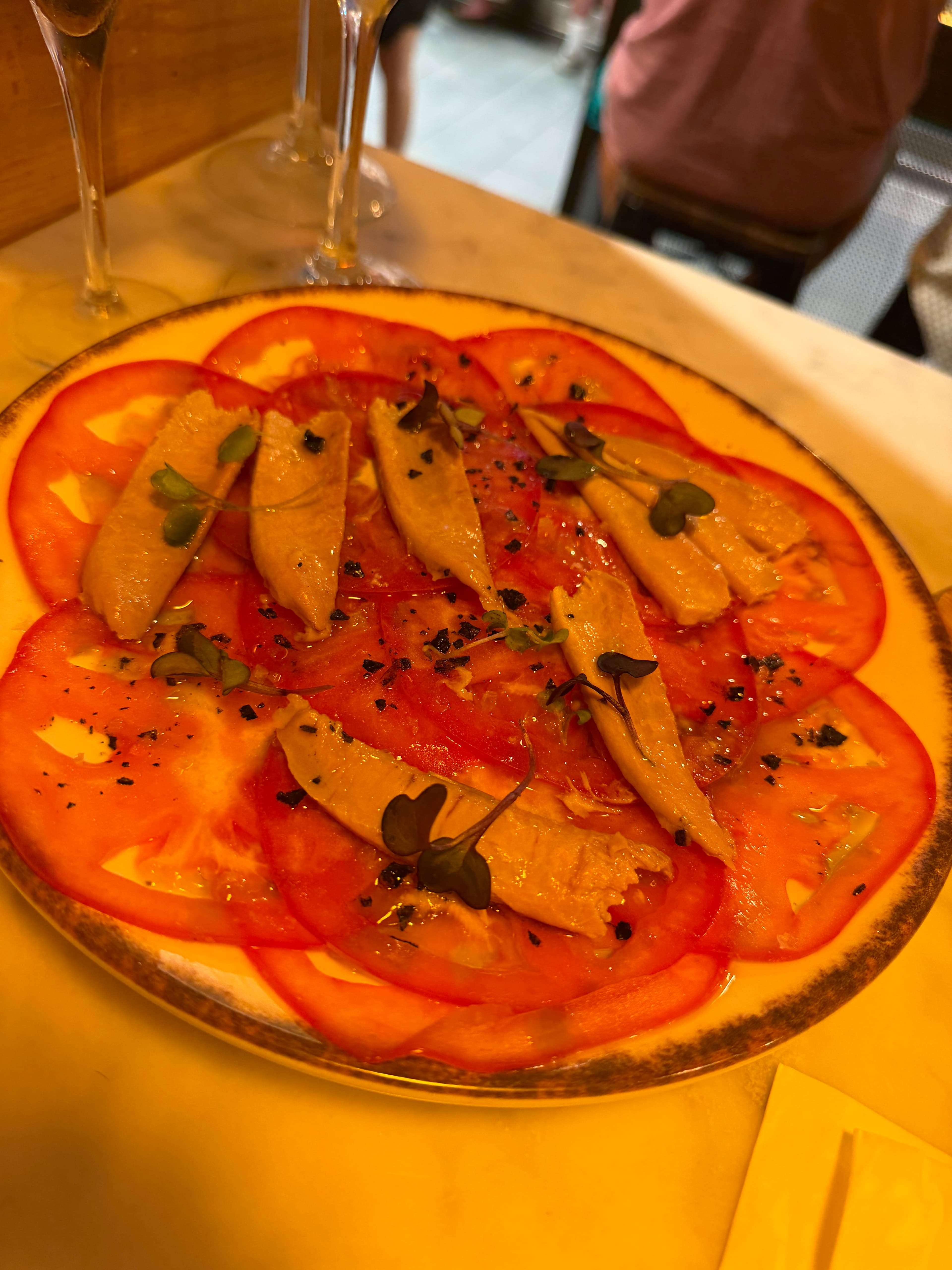 Tomatencarpaccio mit marinierten Fischfilets, Olivenöl und Kräutern in Palma
