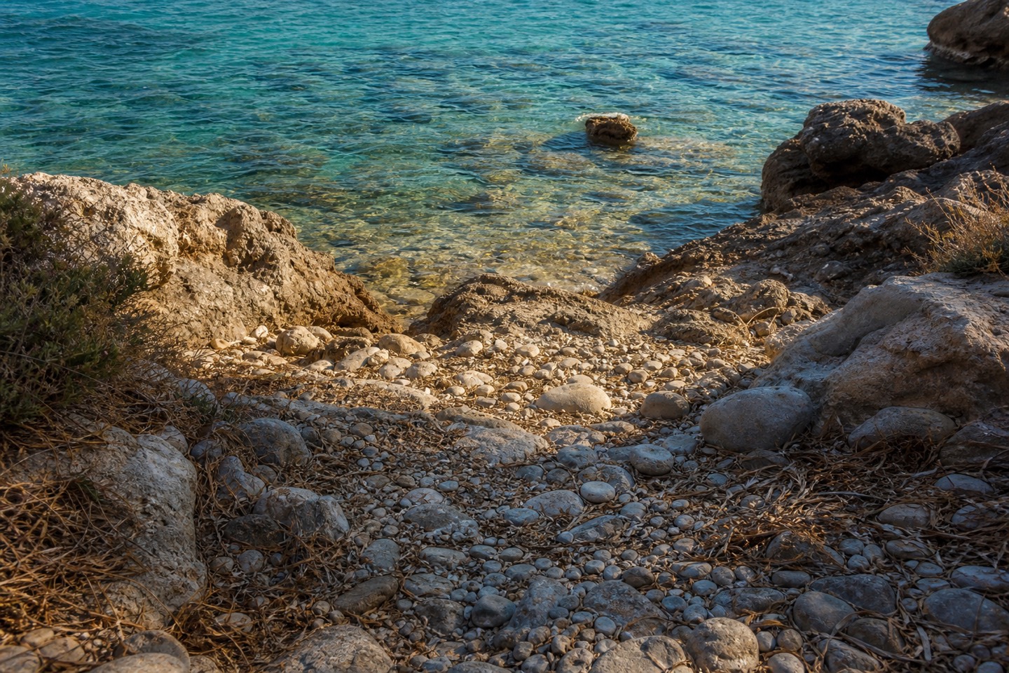 KI-generiertes Stimmungsbild eines unebenen Kies- und Felszugangs zum Wasser im Stil der Cala Carbó