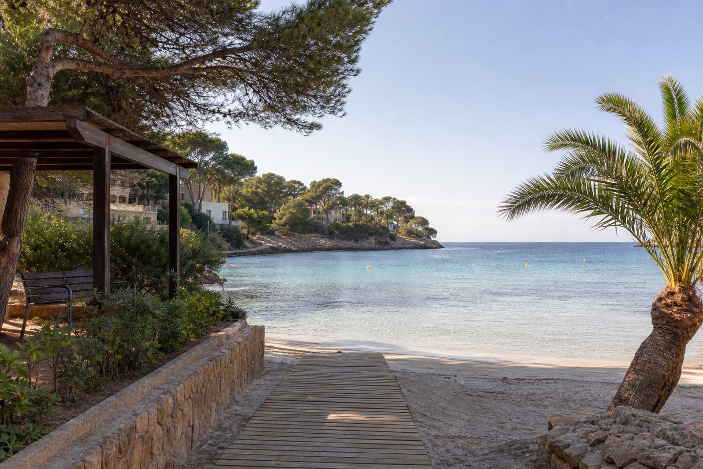 KI-generiertes Stimmungsbild eines Holzstegs mit Schattenplatz, Palmen, Pinien und flachem Wasser an Cala Vinyes
